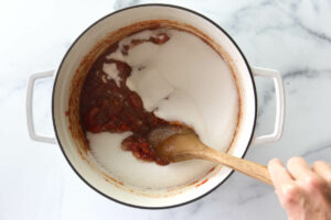Stirring sugar into the tomato jam mixture.