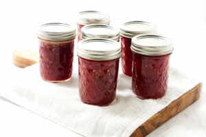 Six jars of spiced tomato preserves on a counter.