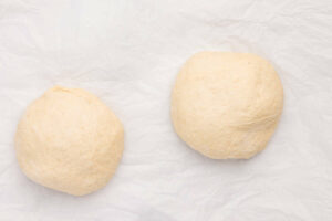 Dividing pizza dough into two portions.