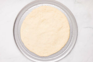 Stretching dough on a round pizza pan.