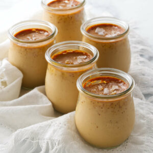 Several jars of baked caramel custard topped with flaky salt.