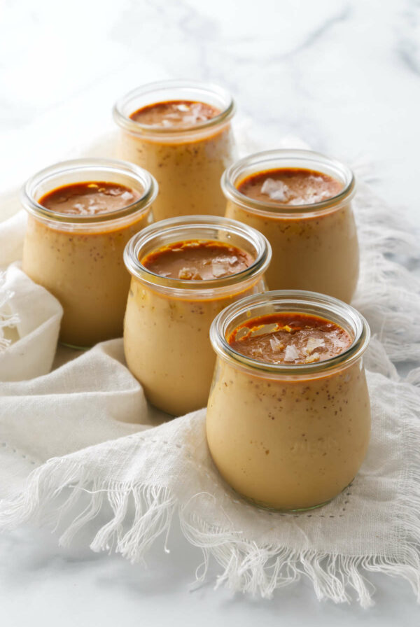 Several jars of baked caramel custard topped with flaky salt.