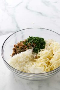 Cheese and sausage and herb in a bowl.