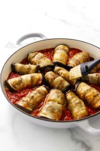 Eggplant involtini rolls in a large skillet.