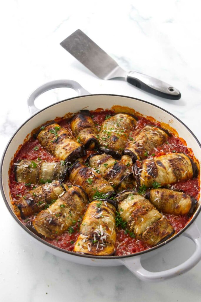 Stuffed eggplant rolls in a baking dish.