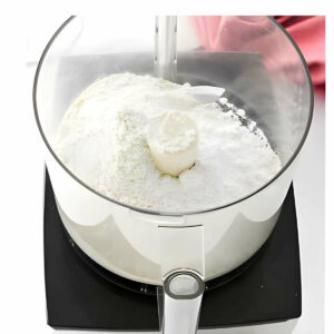 Adding dry ingredients to a food processor.