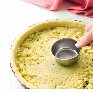 Pressing pastry into a tart pan.