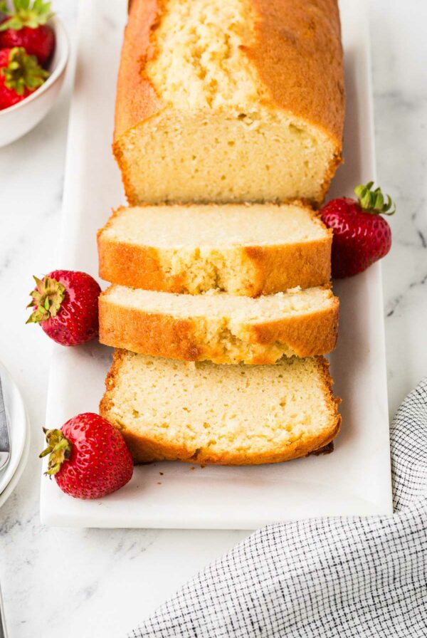 A pound cake sliced and sitting on a white plate.