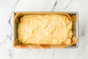 Spreading sourdough pound cake batter in a loaf pan.
