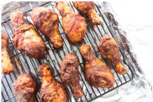 Crispy baked chicken drumsticks on a wire rack over a foil-lined pan.