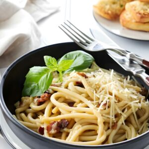 Carbonara pasta with cheese, bacon; fork and spoon on bowl. Wine and bread behind.