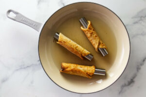 Frying cannoli in a skillet filled with oil.