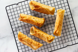 Several cannoli shells cooling on a wire rack.