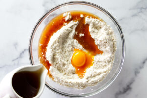 Adding the egg yolk and marsala wine to the cannoli dough.