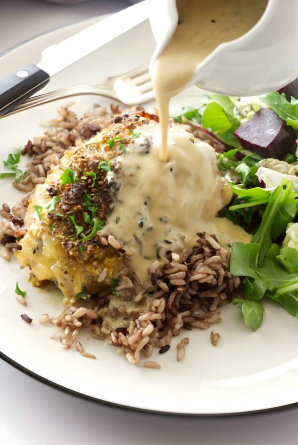 Stuffed chicken breast with sauce, rice, greens, and beet salad on plate.