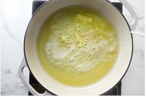 Overhead view of white pot on stove with browning melted butter.