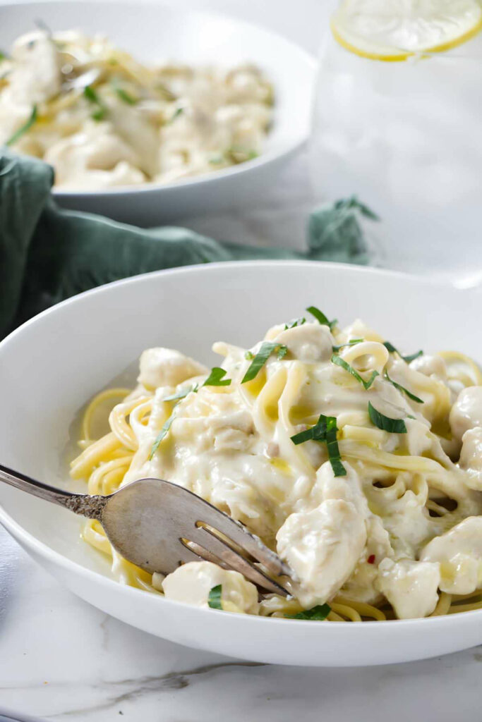 A fork in a pasta bowl with garlic butter pasta.