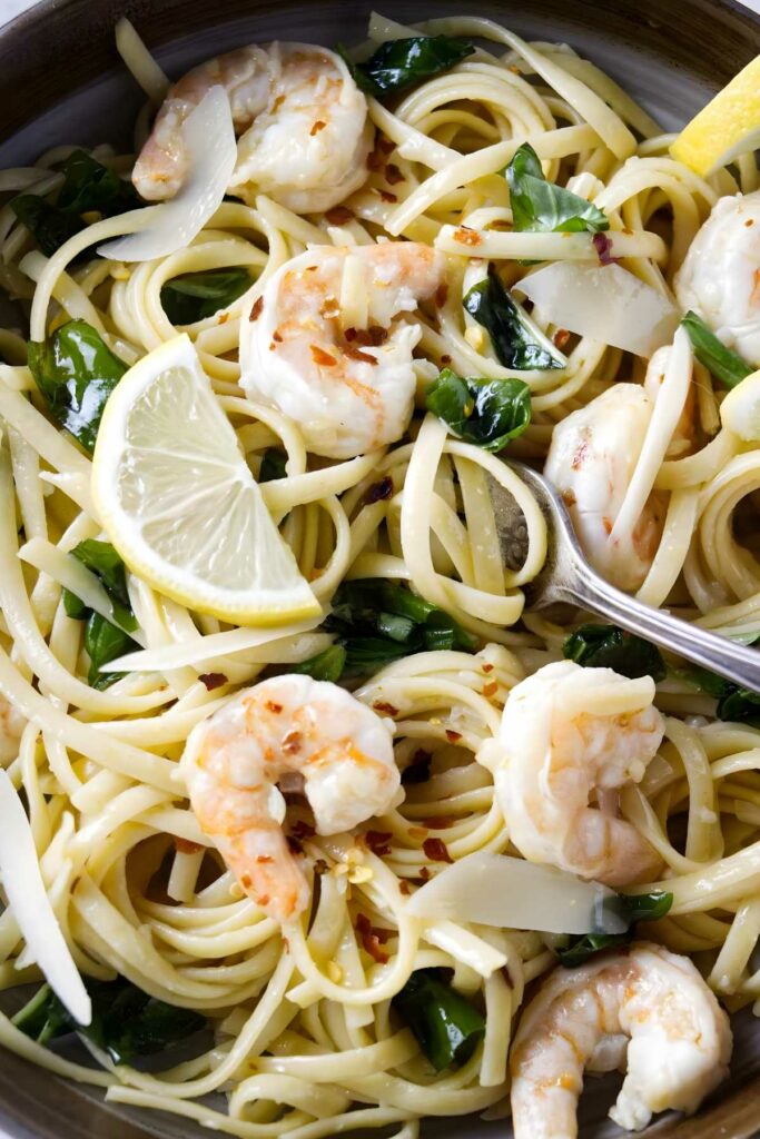 Linguine pasta with shrimp, spinach, lemon, parmesan in a pan.