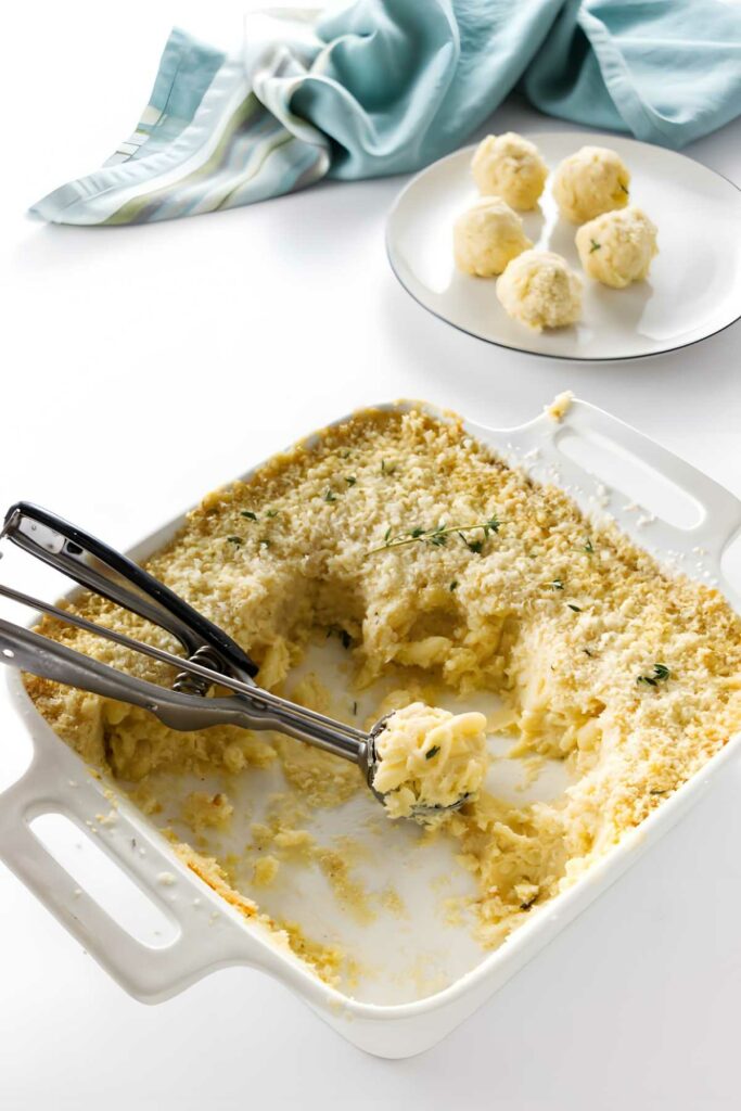 Baked macaroni and cheese in a white dish with breadcrumb topping, scoop lifted.