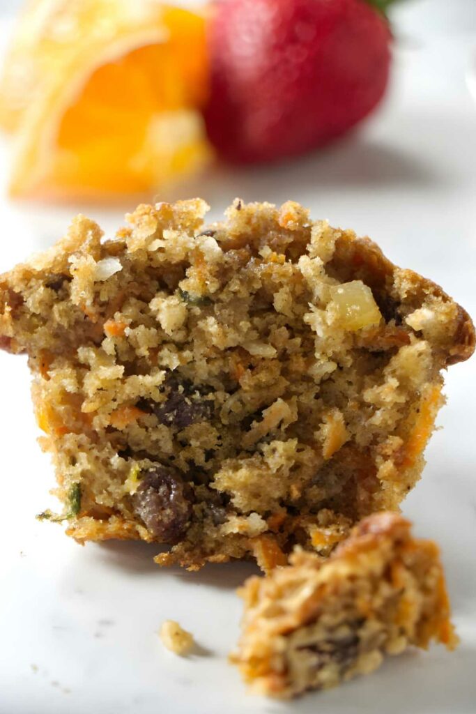 Close-up of a partially eaten muffin with carrot, raisins, and nuts.