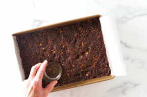 Pressing the crumb mixture into the bottom of a 13 x 9 inch pan for the base of the bars.