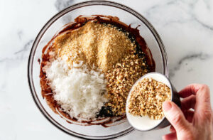 Adding nuts and coconut to the chocolate mixture.