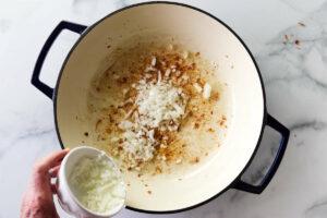 Adding onions to a skillet.