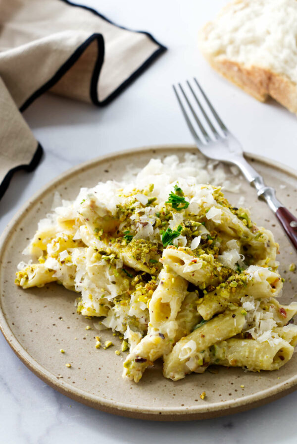 A pasta pistachio recipe on a plate with a fork.