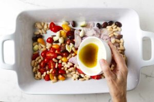 Drizzling a vinaigrette over the tomatoes.