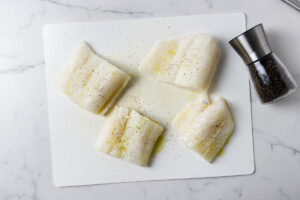 Seasoning the cod fillets with salt and pepper.