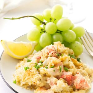 Seafood mac n cheese with parsley, lemon wedge, green grapes, and a fork.