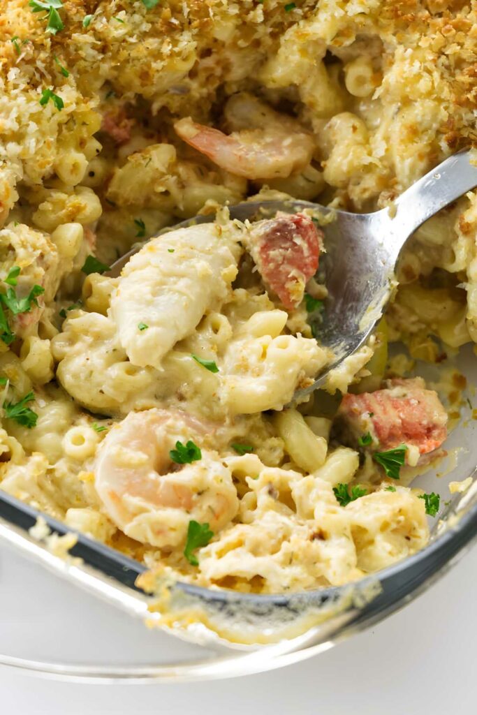 Seafood macaroni and cheese casserole in glass dish, spoon scooping portion.