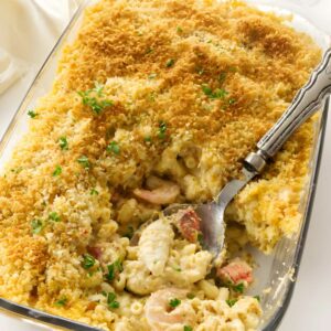 Seafood macaroni and cheese in a glass dish with golden breadcrumbs.