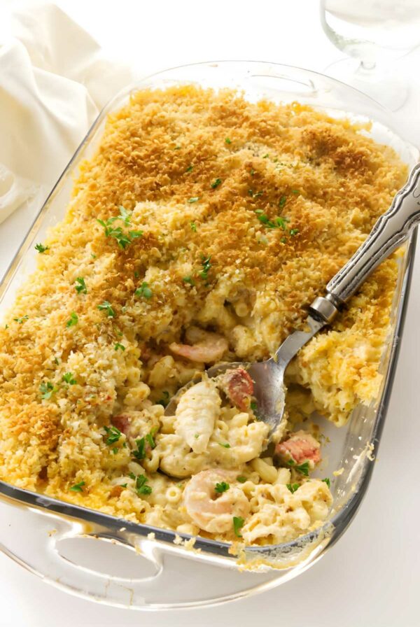 Seafood macaroni and cheese in a glass dish with golden breadcrumbs.