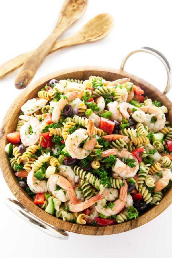 Wooden bowl of pasta salad with shrimp and vegetables.