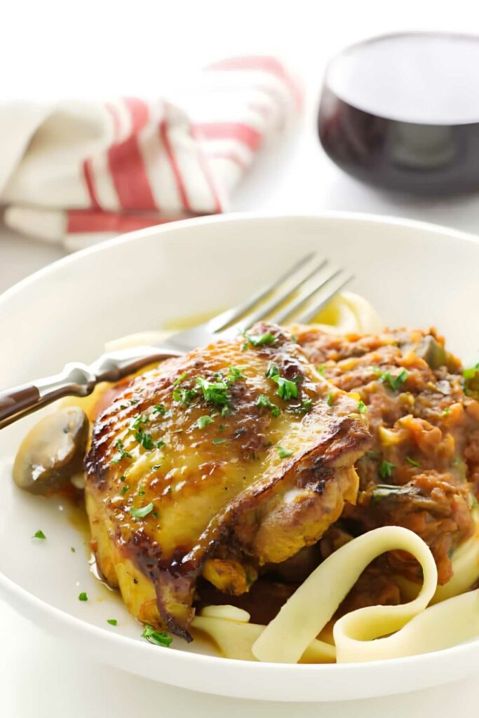 Roasted chicken thigh on pasta with herbs and tomato sauce. 