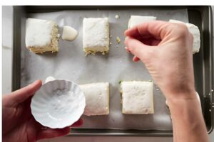 Sprinkling salt on onion biscuits on parchment-lined baking sheet.