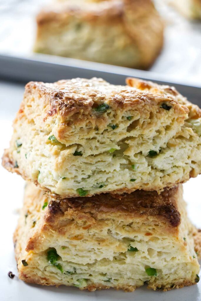 Two stacked golden-brown biscuits, with a blurred biscuit in the background.
