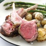Plate of medium-rare lamb, baby potatoes, asparagus, and sautéed onion.