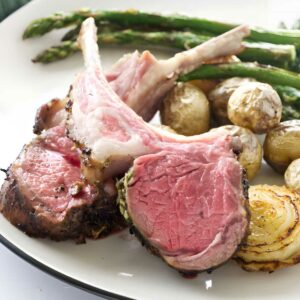 Plate of medium-rare lamb, baby potatoes, asparagus, and sautéed onion.