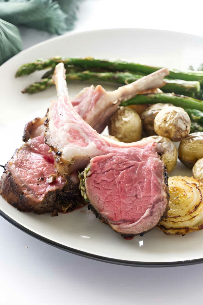 Plate of medium-rare lamb, baby potatoes, asparagus, and sautéed onion.