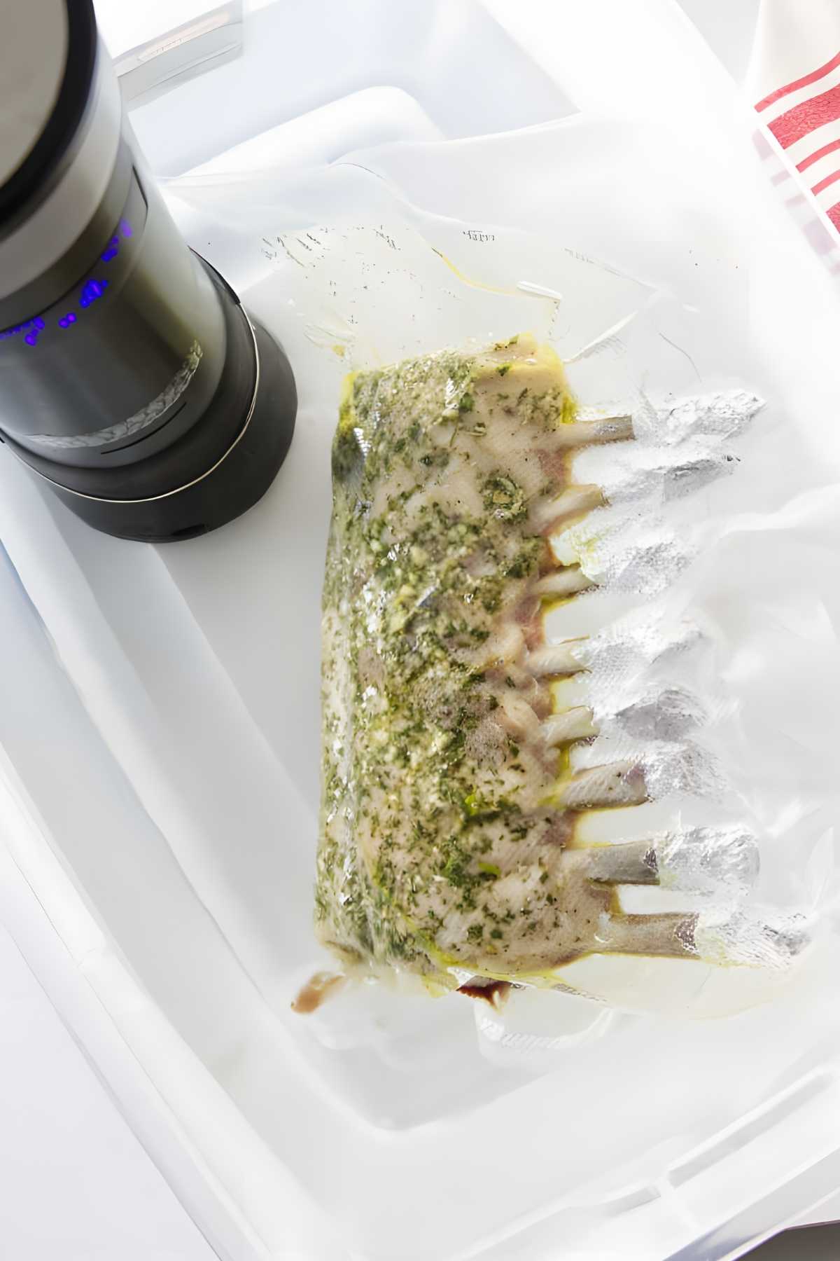 Vacuum-sealed rack of lamb with herbs sous vide in water bath.