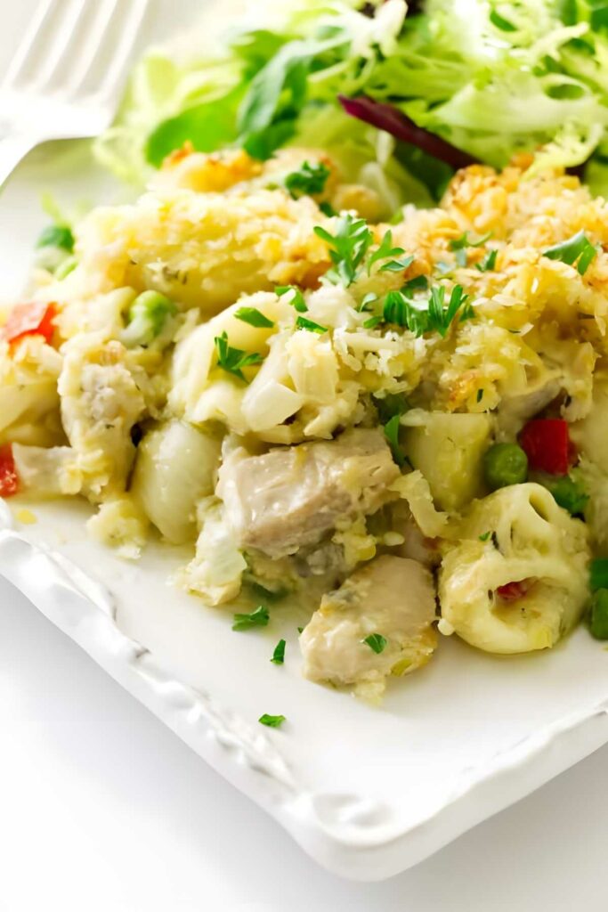 Creamy tuna pasta casserole with peas and peppers on a white plate.
