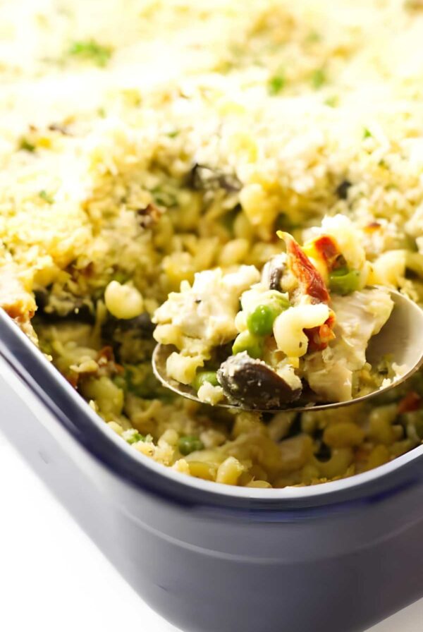 Creamy tetrazzini in casserole, spoon lifting a serving.