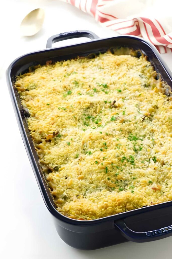 Baked tetrazzini casserole with melted cheese and parsley in a dark rectangular dish.