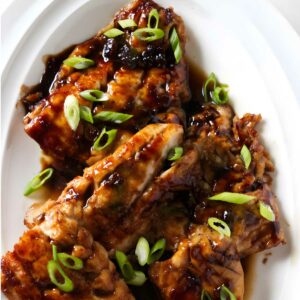 A platter with several soy rockfish fillets topped with scallions.