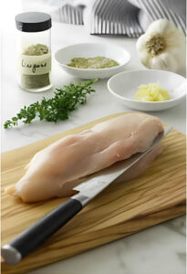 Slicing a chicken breast down the center to create a pocket.