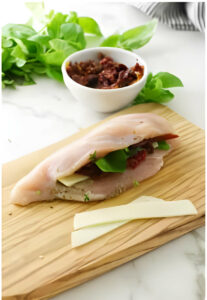 Stuffing a chicken breast with cheese, sun dried tomatoes, and basil.