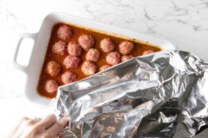 Covering the casserole dish with aluminum foil.
