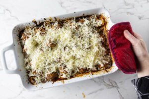 Topping a spaghetti casserole with cheese.
